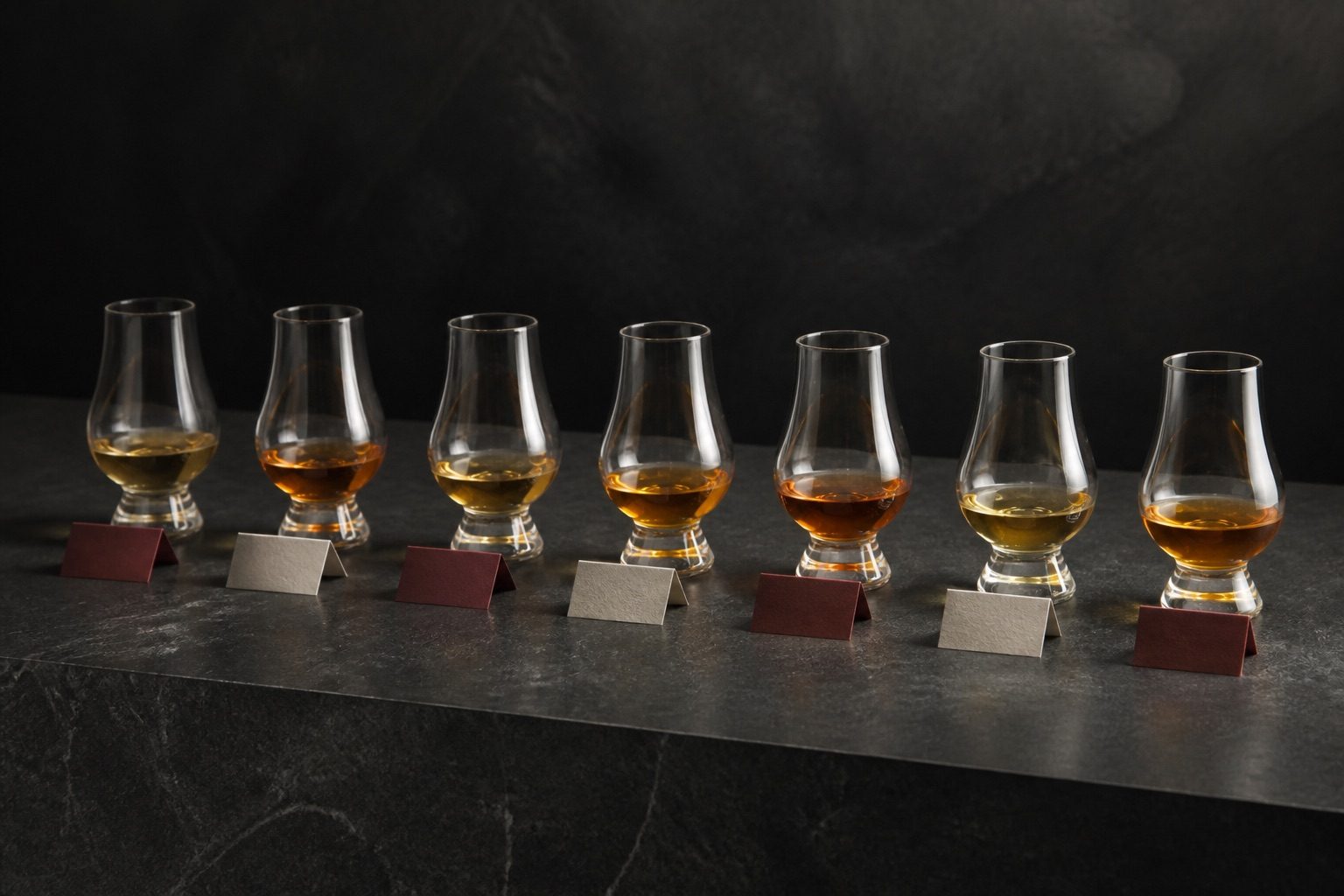 Seven tasting glasses containing whiskies of different colours.
